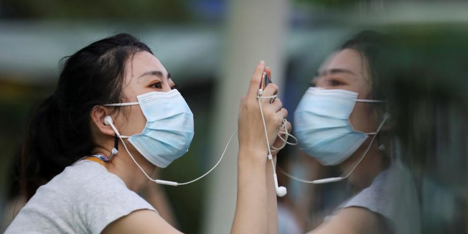 Imagen ilustrativa / Una mujer con mascarilla mira su teléfono móvil en medio del brote del covid-19 en Bangkok, Tailandia