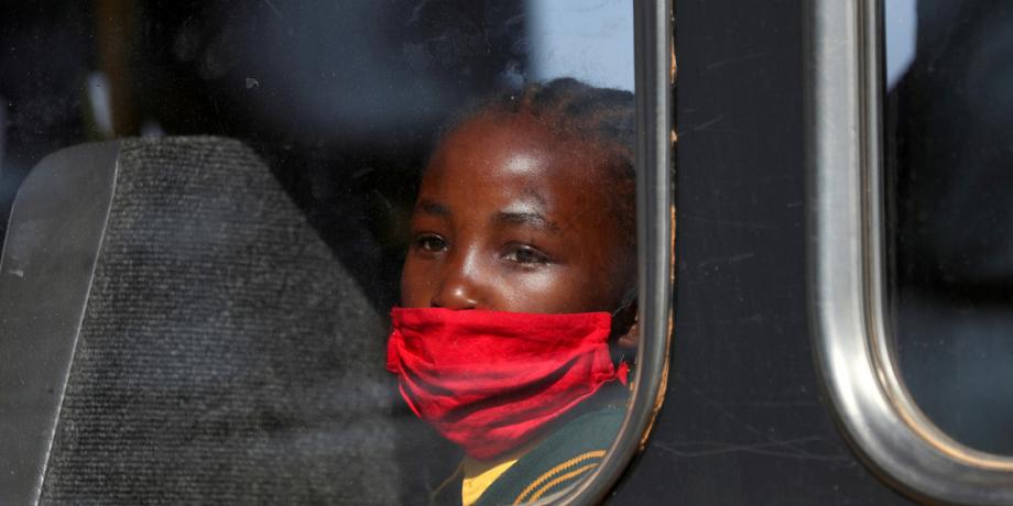 Una niña con mascarilla mira a través de la ventana de un autobús camino a la escuela, Eikenhof, Sudáfrica, el 24 de agosto de 2020.